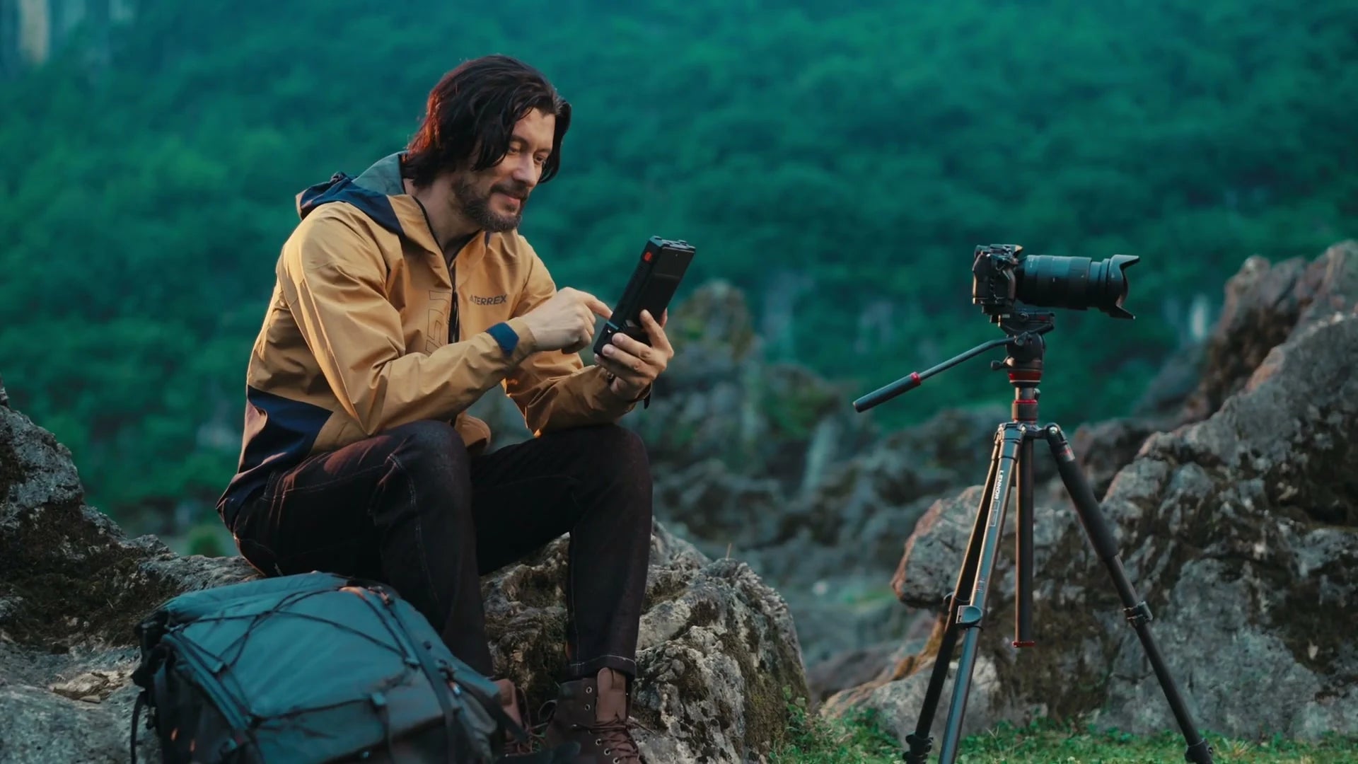 An outdoor creator reviewing PixelMob beside a camera in the mountains